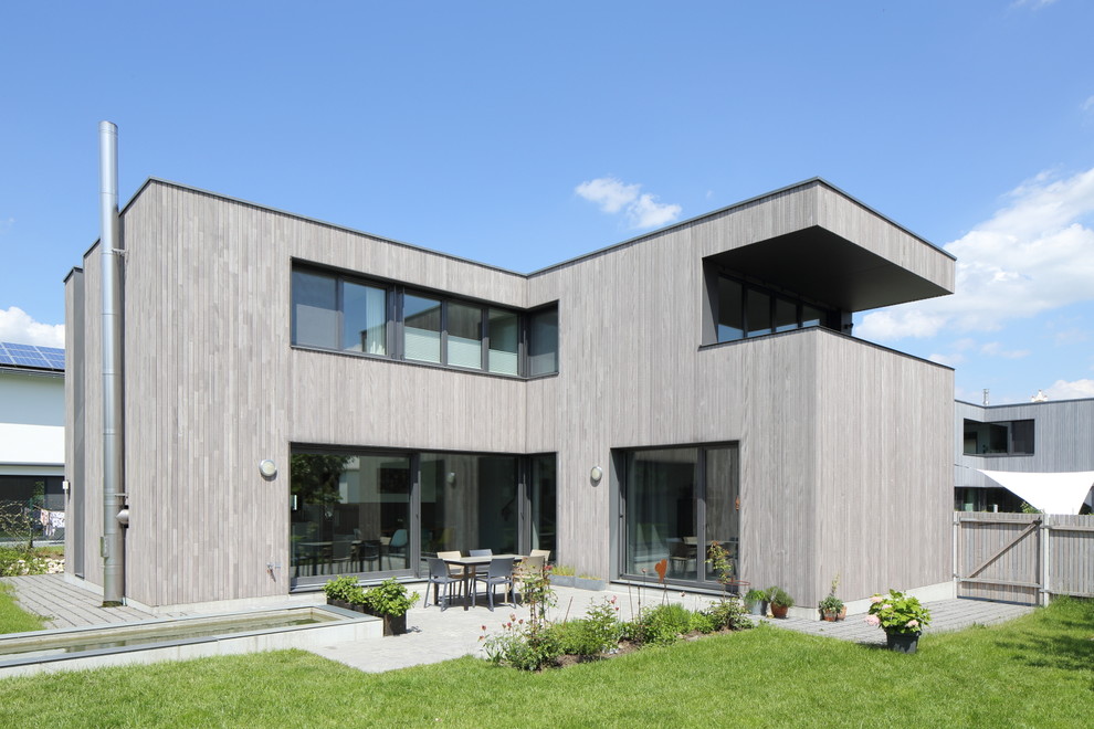 Diseño de fachada gris actual grande de dos plantas con revestimiento de madera y tejado plano