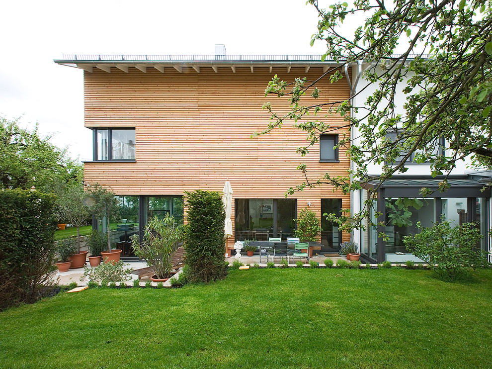 Ejemplo de fachada marrón contemporánea de tamaño medio de tres plantas con revestimiento de madera