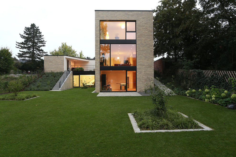 Inspiration for a large and beige contemporary brick house exterior in Dortmund with three floors and a flat roof.