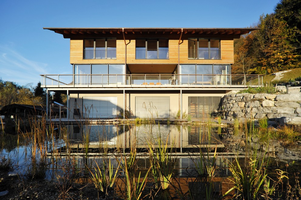 Imagen de fachada de casa gris contemporánea grande de tres plantas con revestimiento de madera, tejado plano y tejado de metal