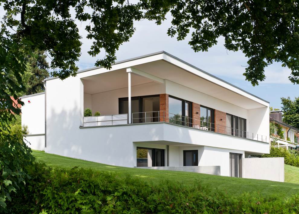 Cette image montre une grande façade de maison blanche minimaliste en bois à un étage avec un toit en appentis.