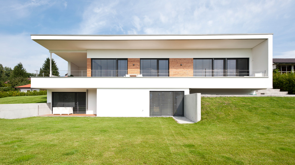 Large and white modern two floor house exterior in Munich with wood cladding and a flat roof.