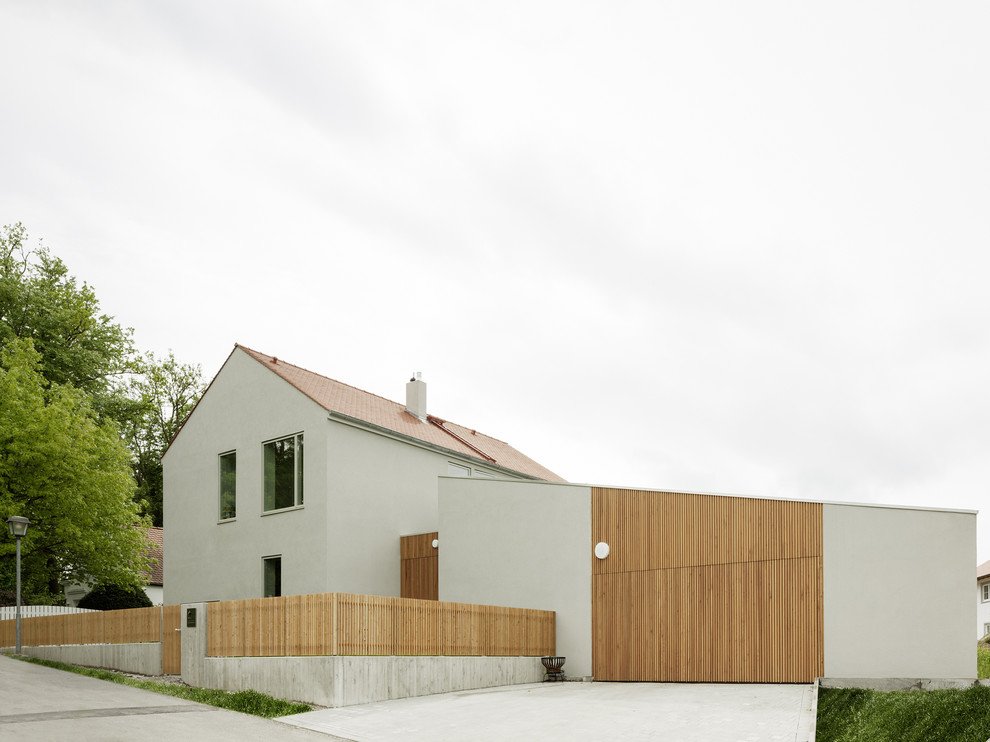 Cette photo montre une façade de maison grise tendance de taille moyenne et à un étage avec un revêtement mixte et un toit à deux pans.