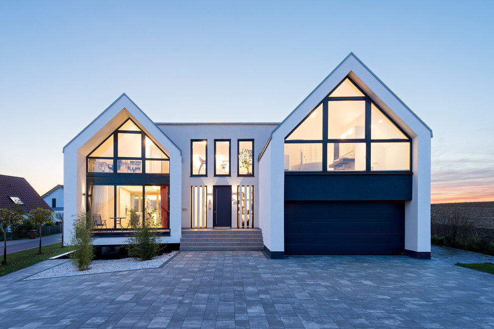 Идея дизайна: большой, белый, двухэтажный частный загородный дом в современном стиле с облицовкой из цементной штукатурки и двускатной крышей