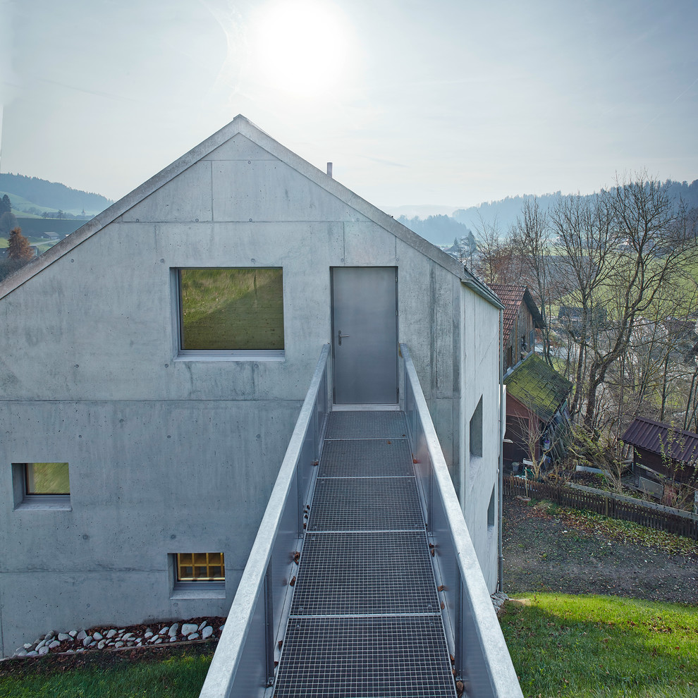 Gey and medium sized industrial concrete house exterior in Dresden with three floors and a pitched roof.
