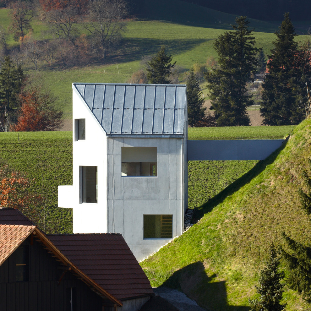 Exemple d'une façade de maison grise moderne en béton de taille moyenne et à niveaux décalés avec un toit à deux pans.