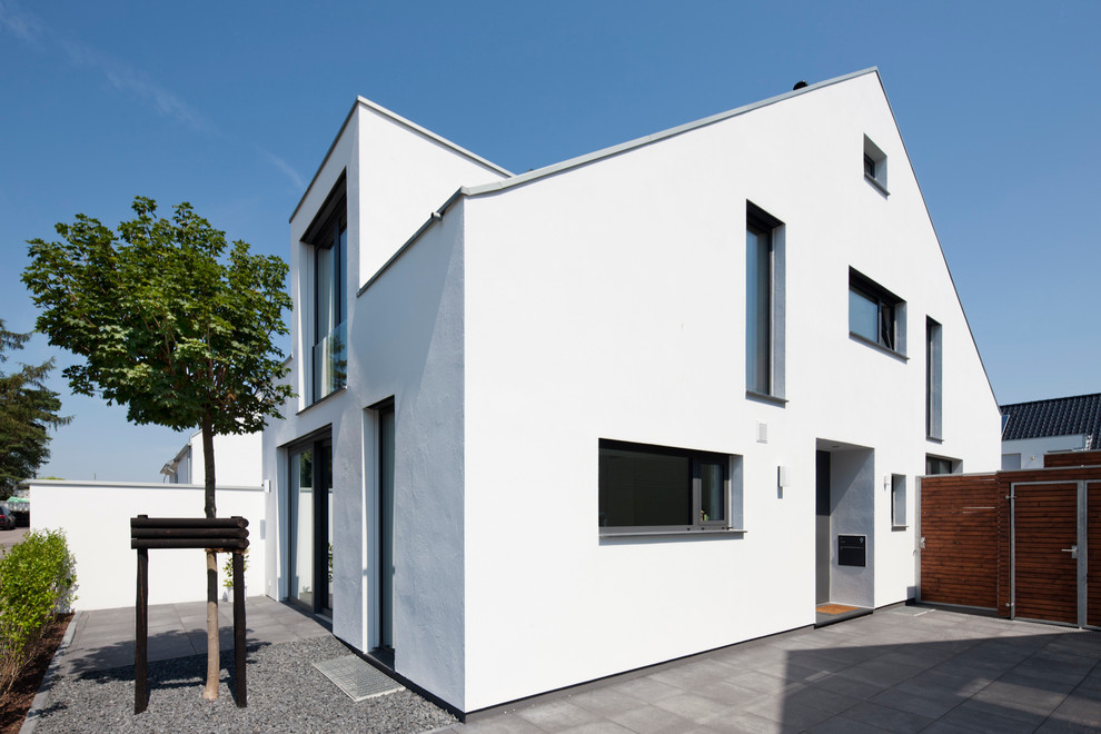 Inspiration for a large and white contemporary render house exterior in Cologne with a pitched roof and three floors.