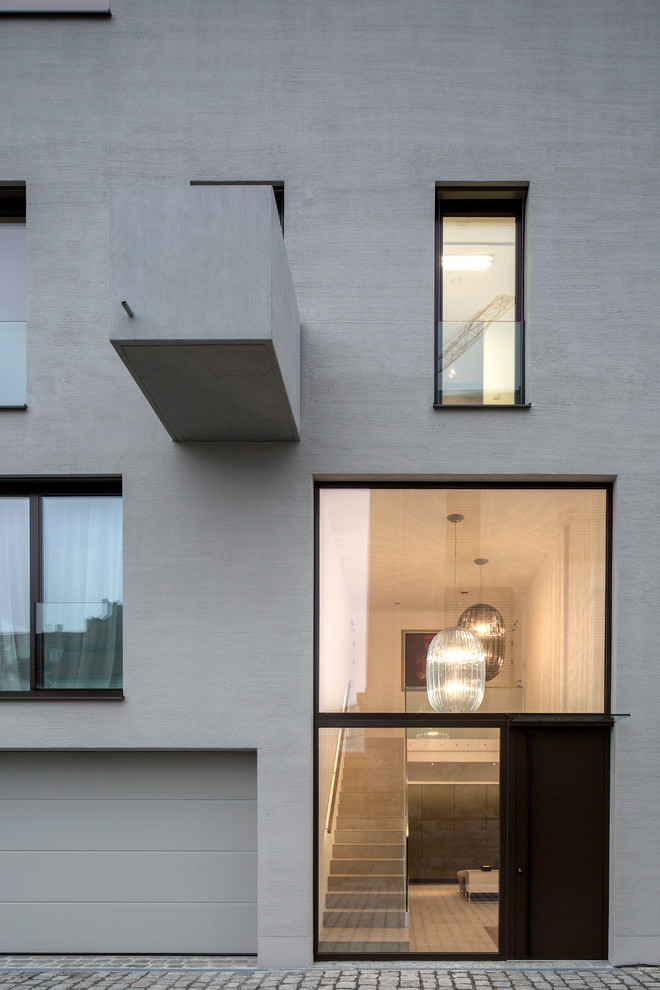 Ejemplo de fachada de casa gris moderna de tamaño medio de tres plantas con revestimiento de estuco y tejado plano