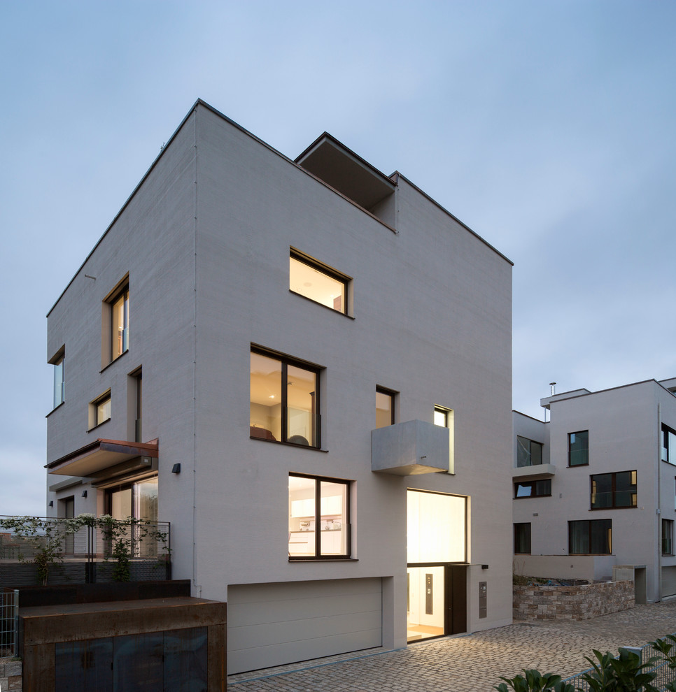 Cette image montre une façade de maison grise minimaliste en stuc de taille moyenne et à deux étages et plus avec un toit plat.