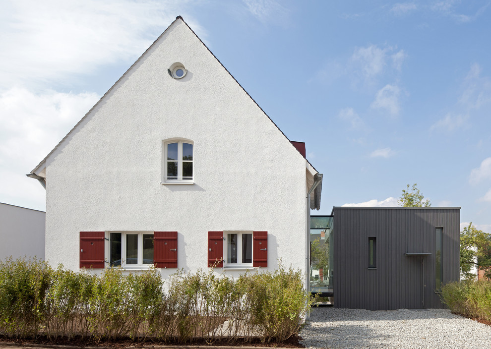 На фото: двухэтажный, белый дом среднего размера в современном стиле с комбинированной облицовкой и двускатной крышей с