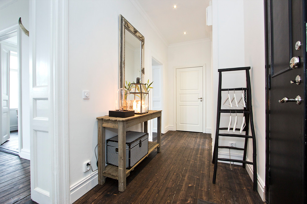 Example of a large danish dark wood floor hallway design in Malmo with white walls