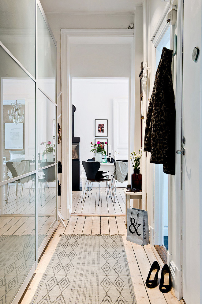 Стильный дизайн: коридор в скандинавском стиле с белыми стенами и светлым паркетным полом - последний тренд
