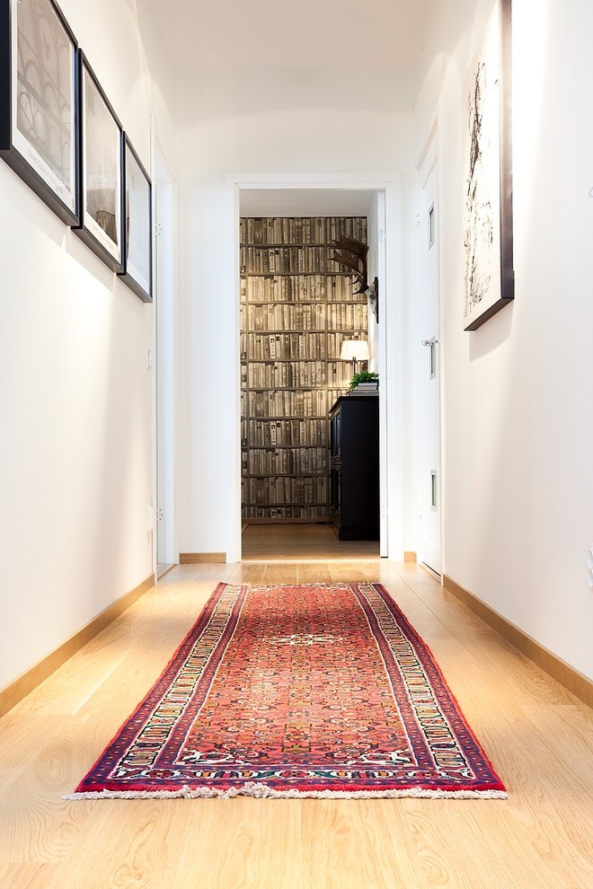 Immagine di un piccolo ingresso o corridoio minimal con pareti bianche, parquet chiaro e pavimento marrone