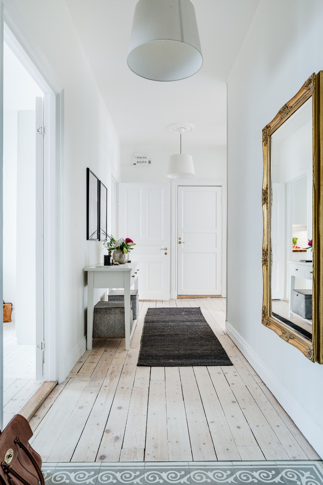 Mid-sized danish light wood floor hallway photo in Gothenburg with white walls