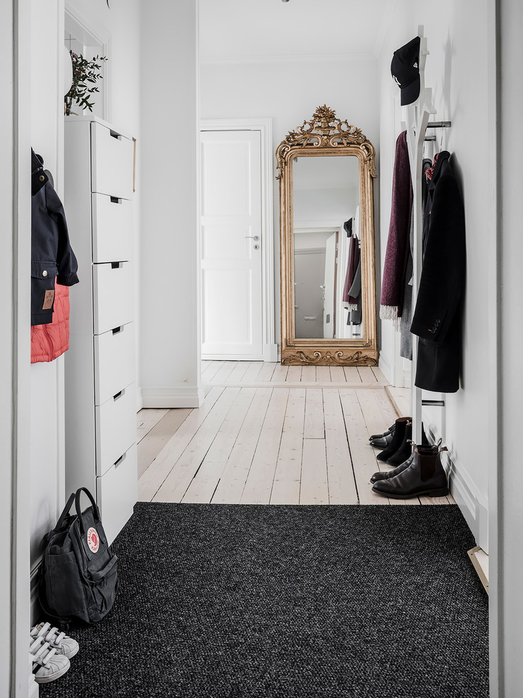 Bild på en minimalistisk hall, med ljust trägolv och beiget golv