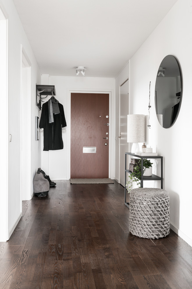 На фото: коридор среднего размера в скандинавском стиле с белыми стенами, темным паркетным полом и коричневым полом