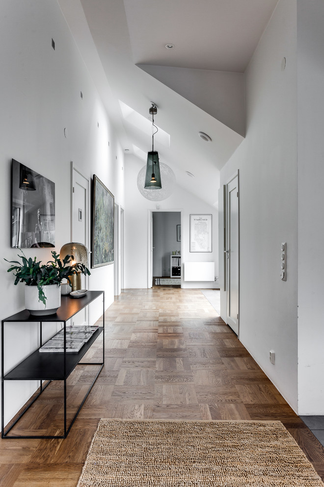 Стильный дизайн: коридор среднего размера в скандинавском стиле с белыми стенами и светлым паркетным полом - последний тренд