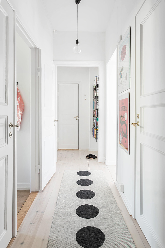 На фото: коридор в скандинавском стиле с белыми стенами и светлым паркетным полом с