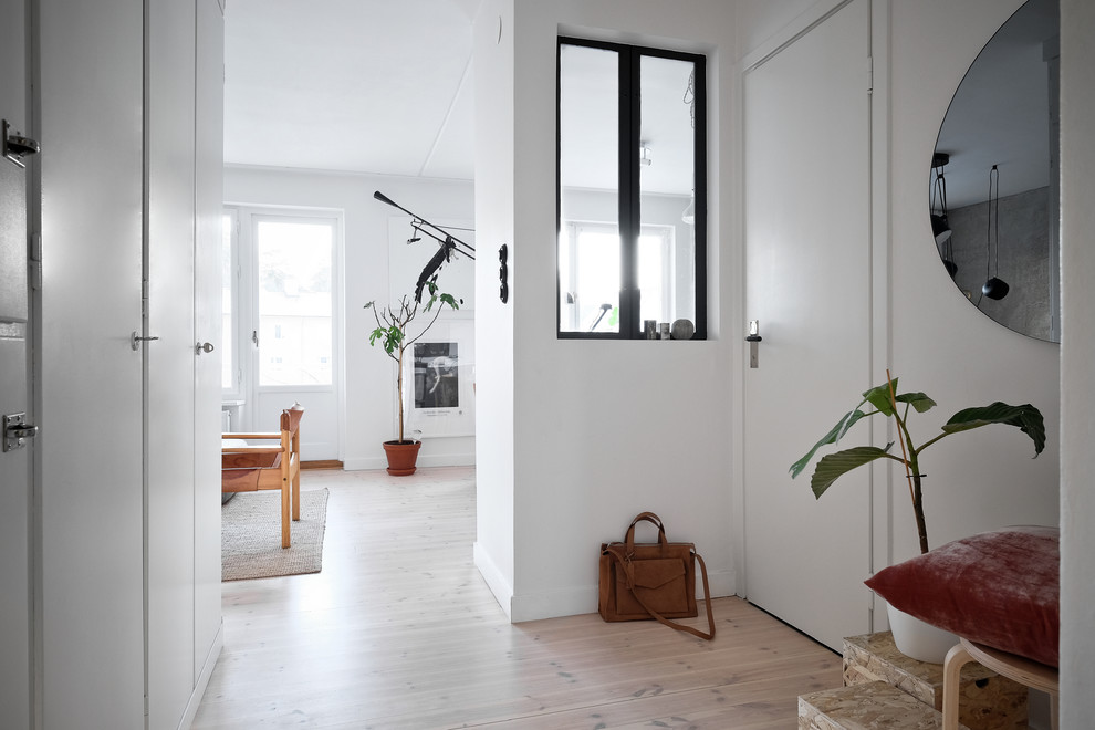 Idéer för en skandinavisk hall, med vita väggar, ljust trägolv och vitt golv