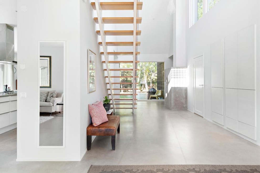 Cette image montre un couloir minimaliste de taille moyenne avec un mur blanc et sol en béton ciré.