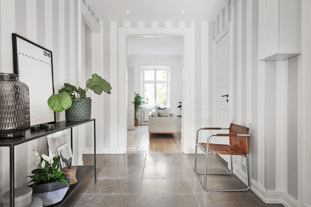 Стильный дизайн: коридор среднего размера в скандинавском стиле с серыми стенами и полом из известняка - последний тренд