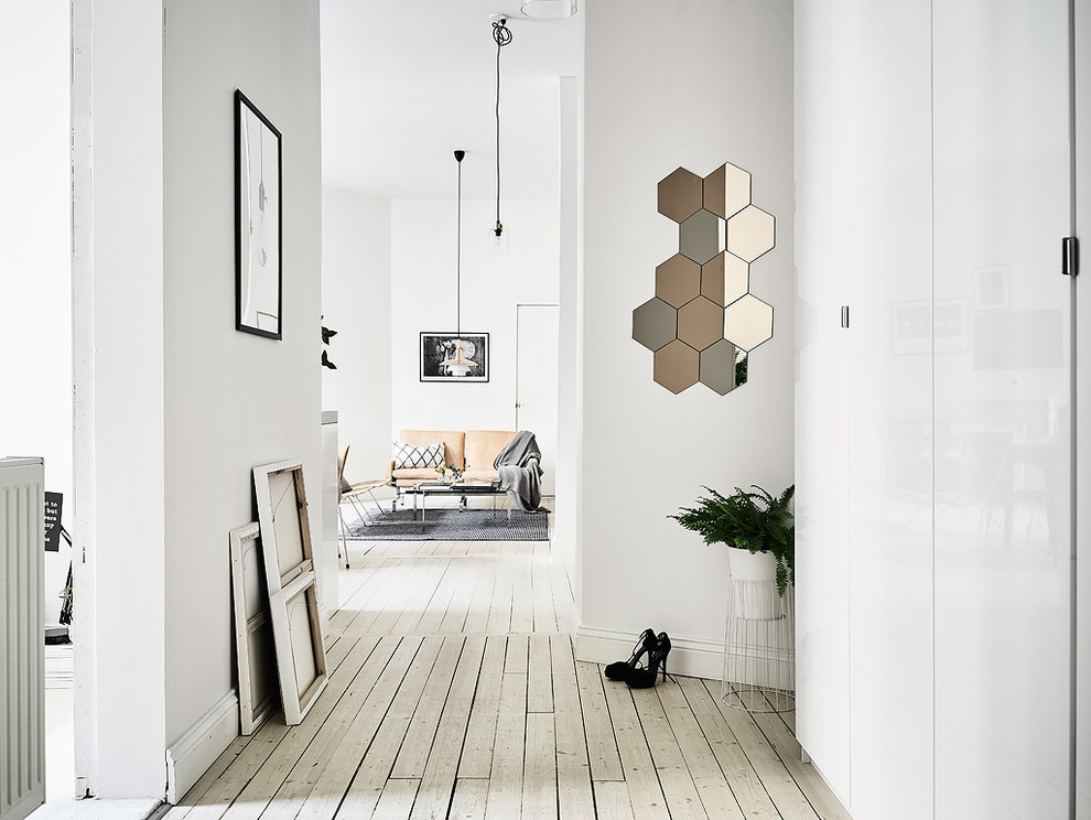 На фото: коридор среднего размера в скандинавском стиле с белыми стенами и светлым паркетным полом с