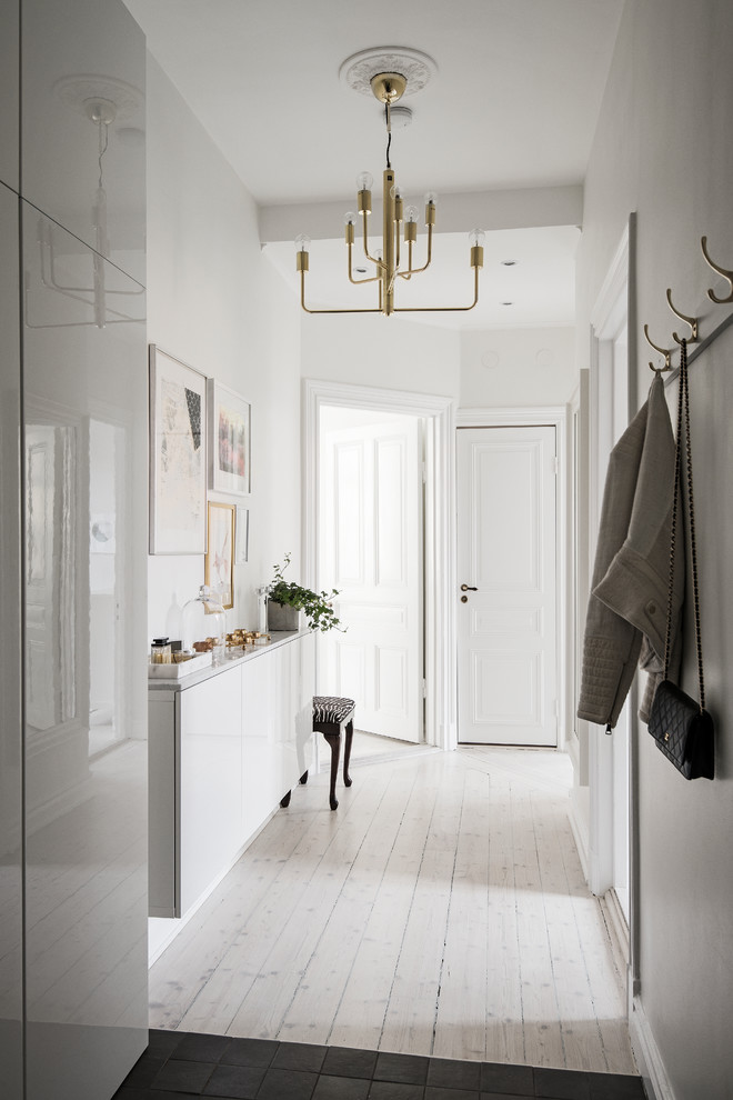 Aménagement d'un couloir scandinave avec un mur blanc, parquet clair et un sol beige.