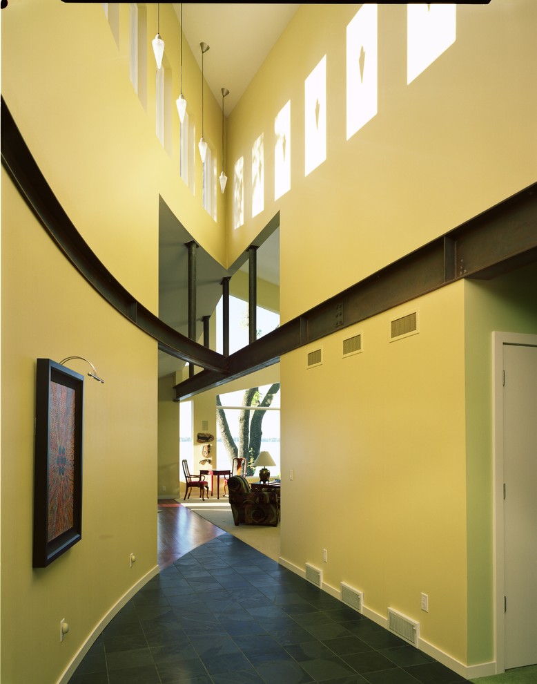 Diseño de recibidores y pasillos actuales grandes con paredes amarillas y suelo de baldosas de porcelana