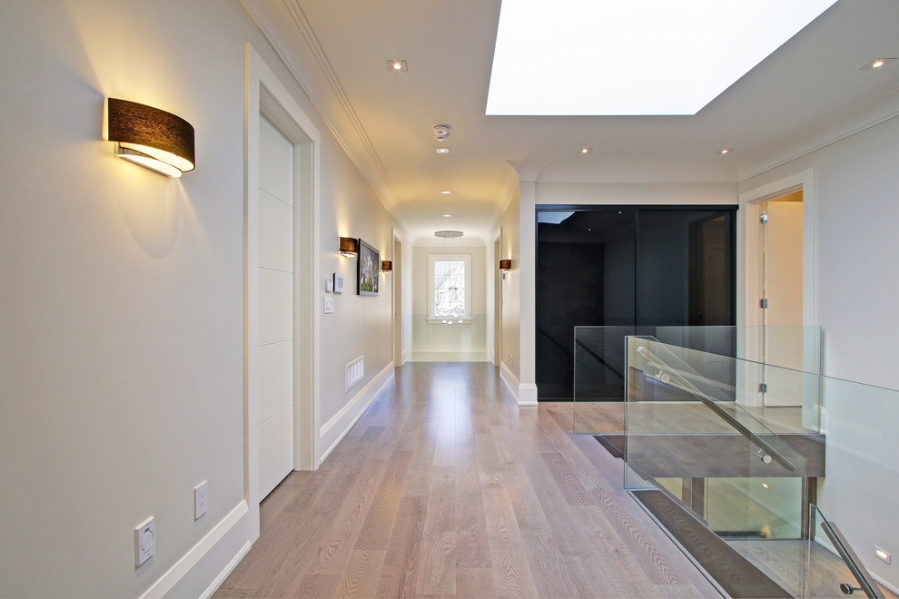Inspiration pour un grand couloir minimaliste avec un mur beige et parquet clair.