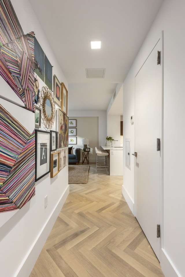 Idées déco pour un couloir contemporain de taille moyenne avec un mur blanc, parquet clair et un sol beige.