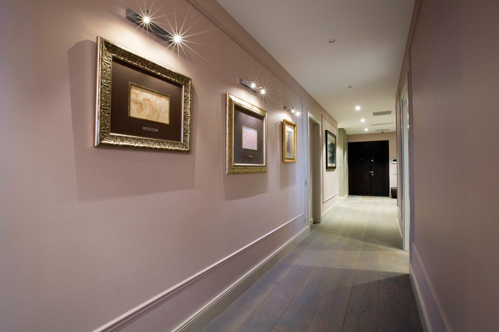 Inspiration pour un couloir design de taille moyenne avec un mur rose et un sol en bois brun.