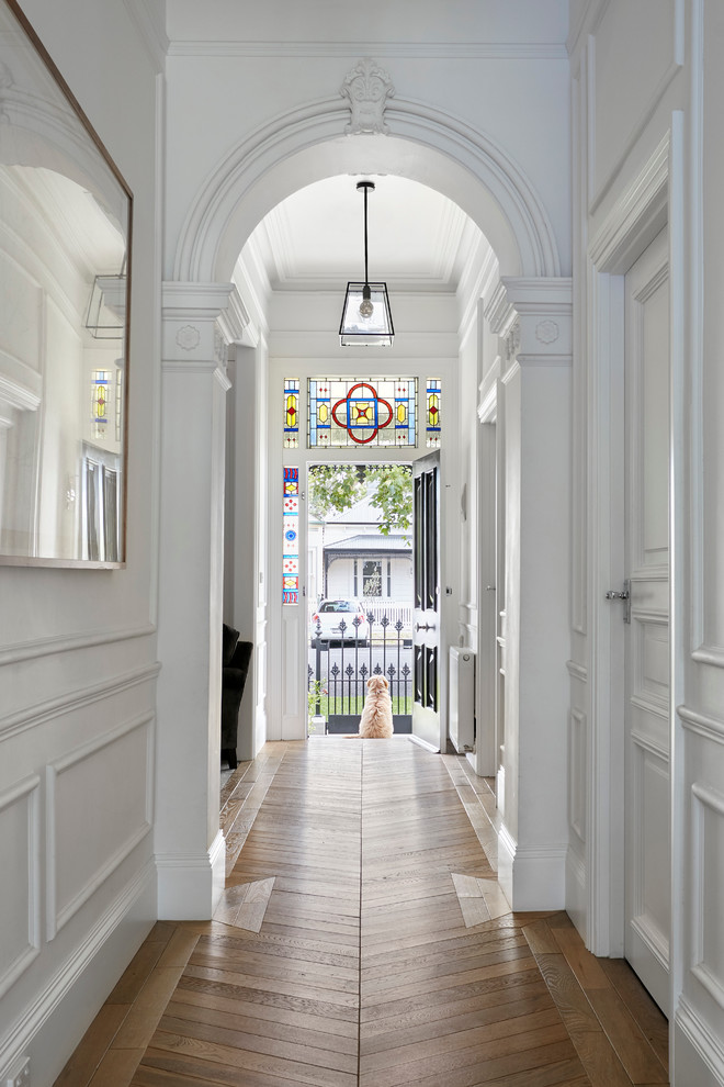 На фото: коридор: освещение в викторианском стиле с белыми стенами и светлым паркетным полом
