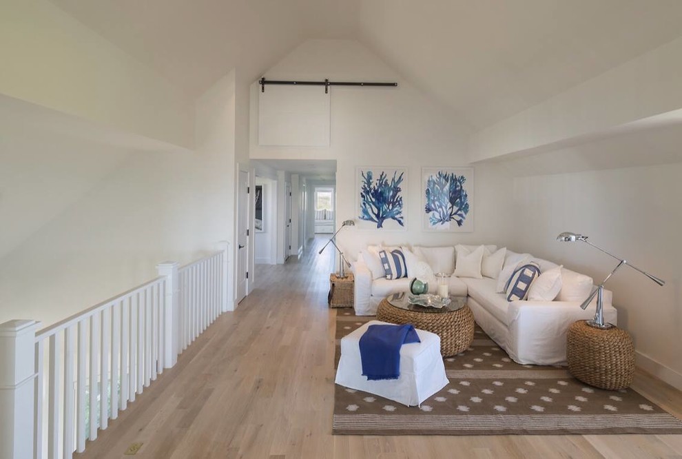 Example of a large beach style light wood floor hallway design in Boston with white walls