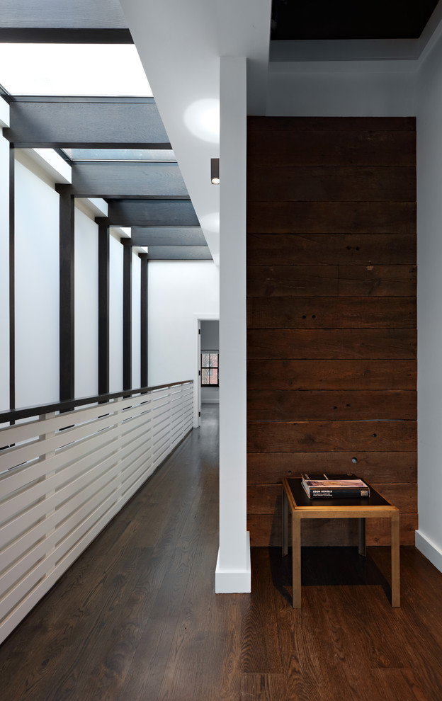 Inspiration pour un couloir minimaliste en bois de taille moyenne avec un mur blanc, parquet foncé et un sol marron.