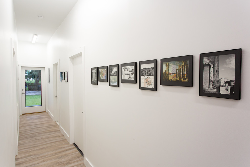 На фото: коридор в стиле модернизм с белыми стенами, светлым паркетным полом и коричневым полом
