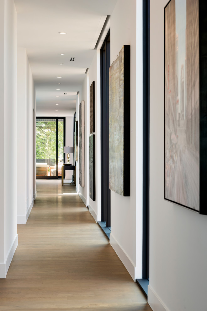 На фото: большой коридор в стиле модернизм с белыми стенами, светлым паркетным полом и серым полом с