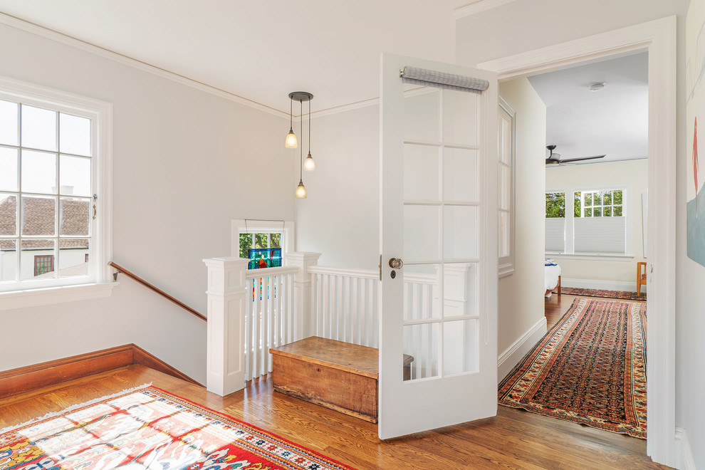 Inspiration pour un couloir craftsman de taille moyenne avec un mur blanc, un sol en bois brun et un sol marron.