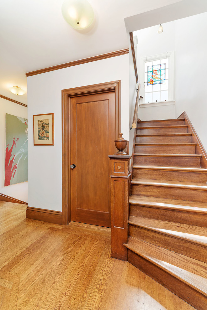Idée de décoration pour un couloir craftsman de taille moyenne avec un mur blanc, un sol en bois brun et un sol marron.