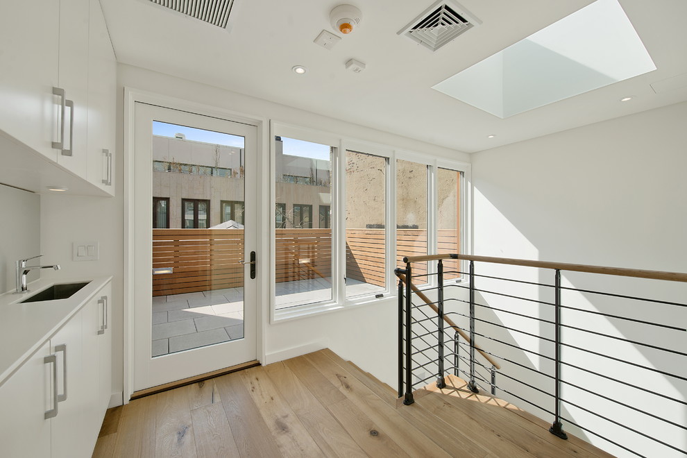 Réalisation d'un couloir design avec un mur blanc et un sol en bois brun.