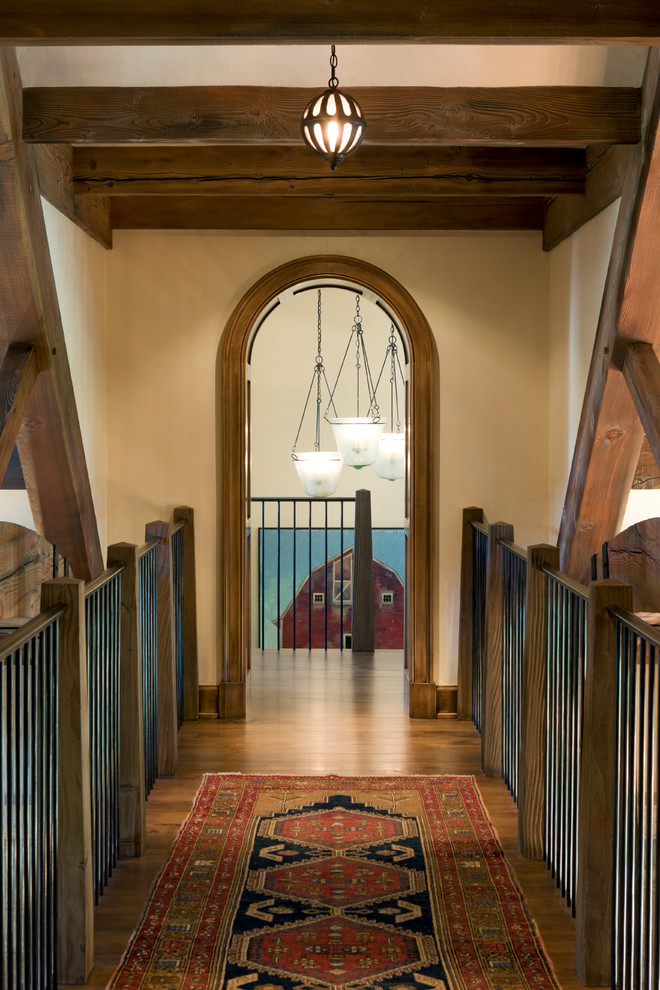 Cette image montre un grand couloir traditionnel avec un mur beige et un sol en bois brun.