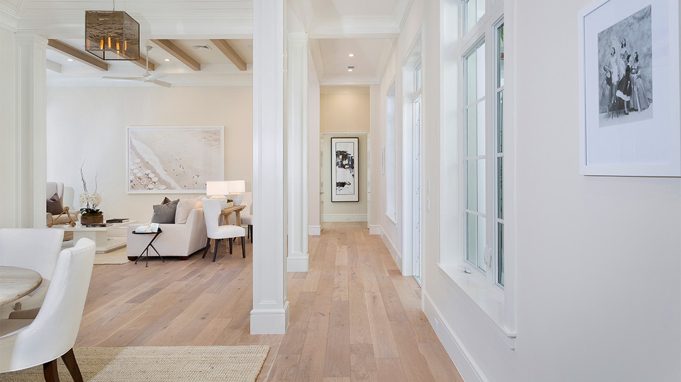 Inspiration for a mid-sized tropical light wood floor and beige floor hallway remodel in Miami with white walls