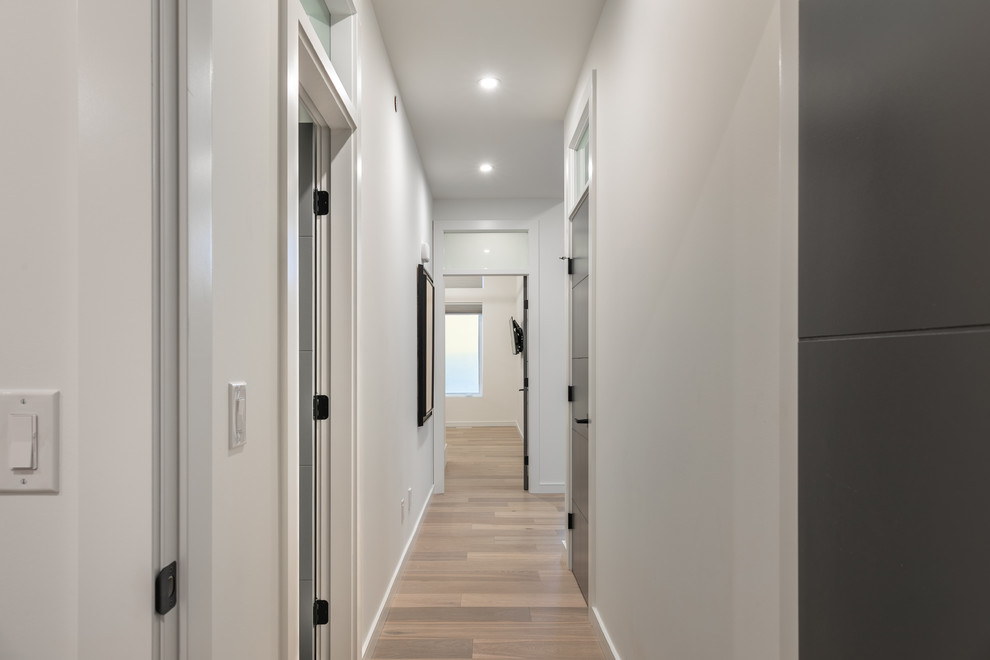 Diseño de recibidores y pasillos minimalistas de tamaño medio con paredes blancas y suelo de madera clara