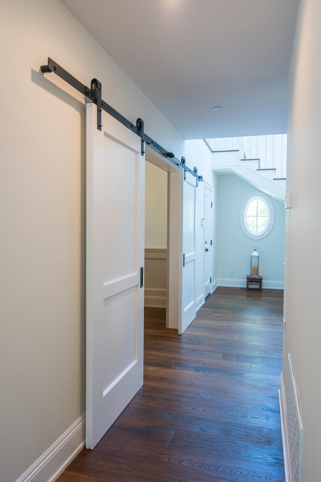 Cette photo montre un couloir chic de taille moyenne avec un mur blanc et un sol en bois brun.