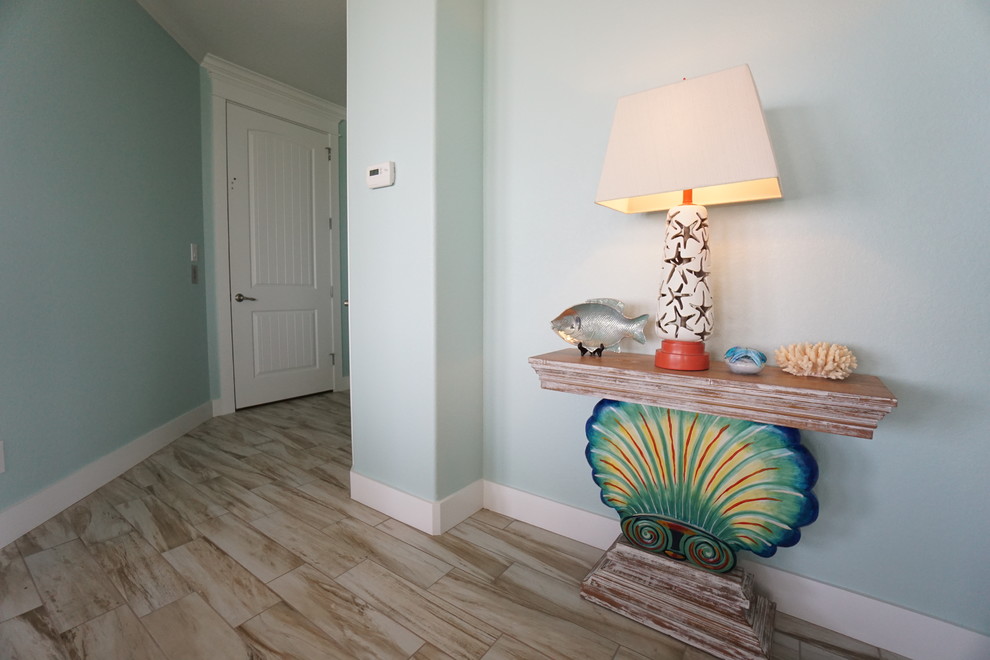 ヒューストンにある低価格の中くらいなビーチスタイルのおしゃれな廊下 (青い壁、磁器タイルの床) の写真
