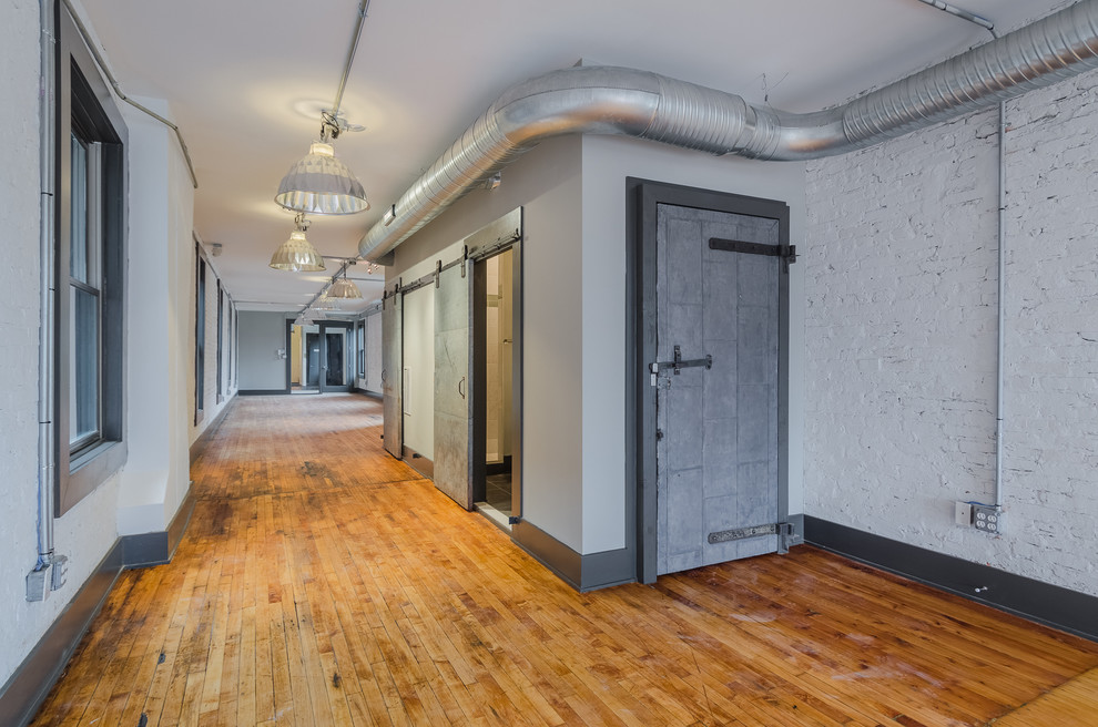 На фото: большой коридор в стиле лофт с серыми стенами и светлым паркетным полом