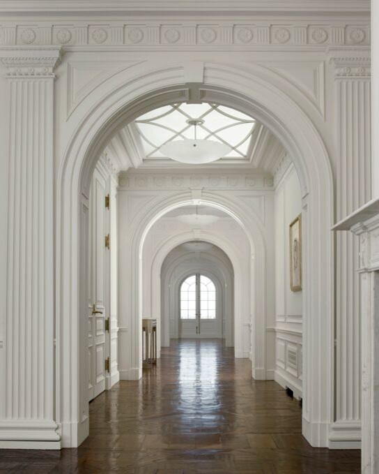 Inredning av en klassisk stor hall, med vita väggar, mörkt trägolv och brunt golv
