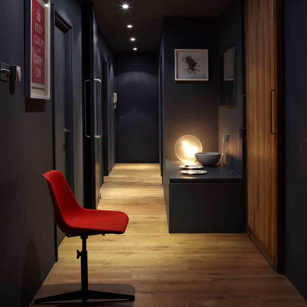 Cette image montre un couloir design avec un mur noir, un sol en bois brun et un sol marron.