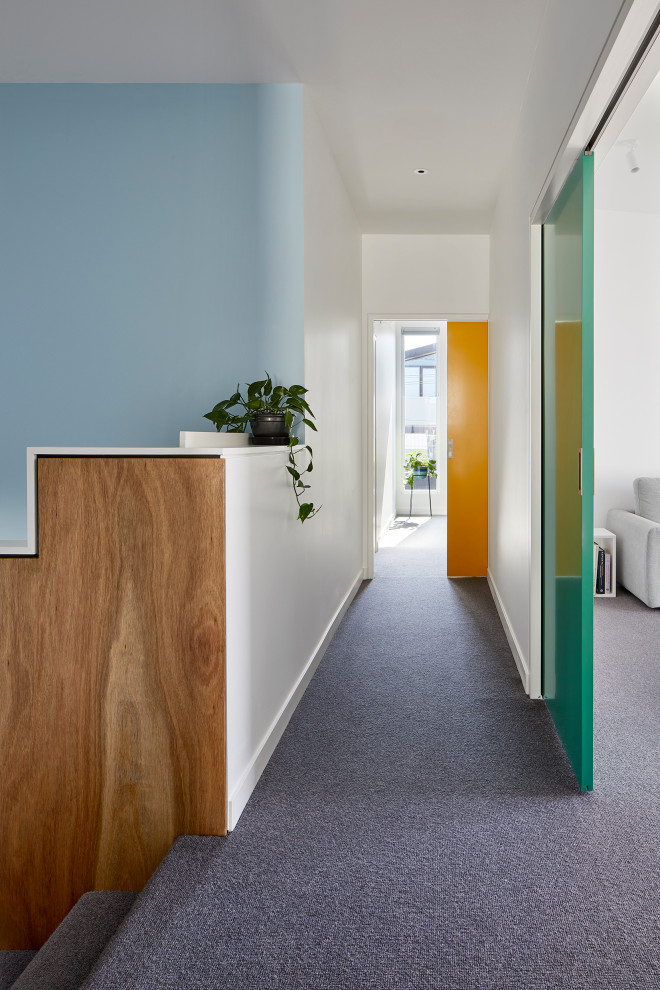 Bild på en mellanstor minimalistisk hall, med blå väggar, heltäckningsmatta och grått golv