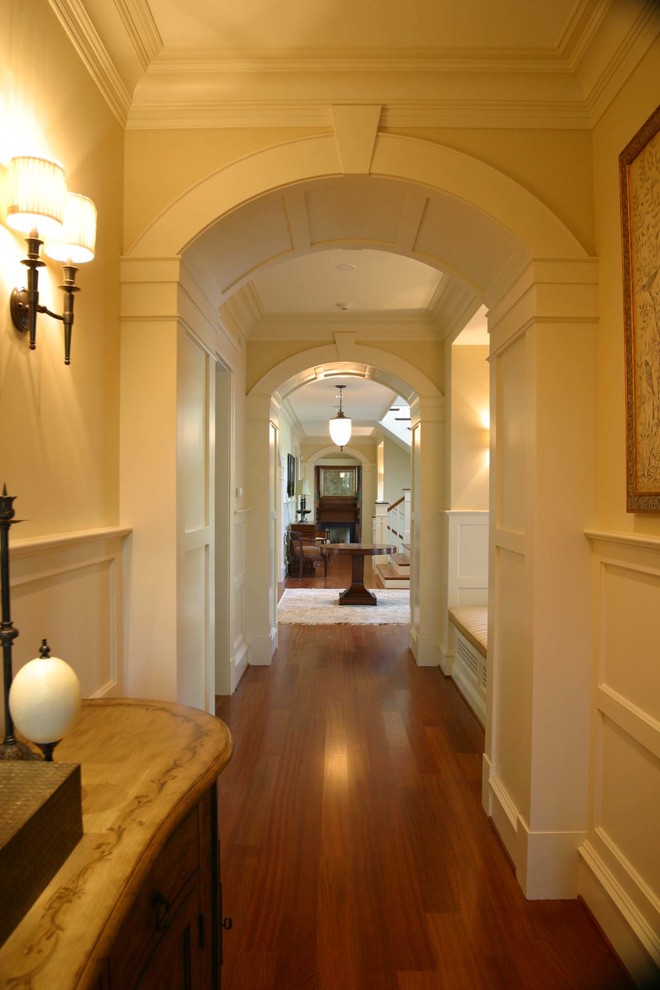 На фото: огромный коридор в классическом стиле с белыми стенами и темным паркетным полом с