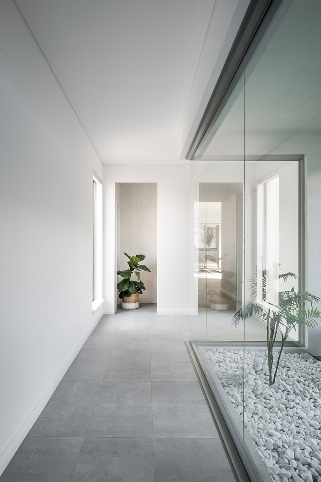 Свежая идея для дизайна: узкий коридор в современном стиле с белыми стенами, полом из керамической плитки и серым полом - отличное фото интерьера